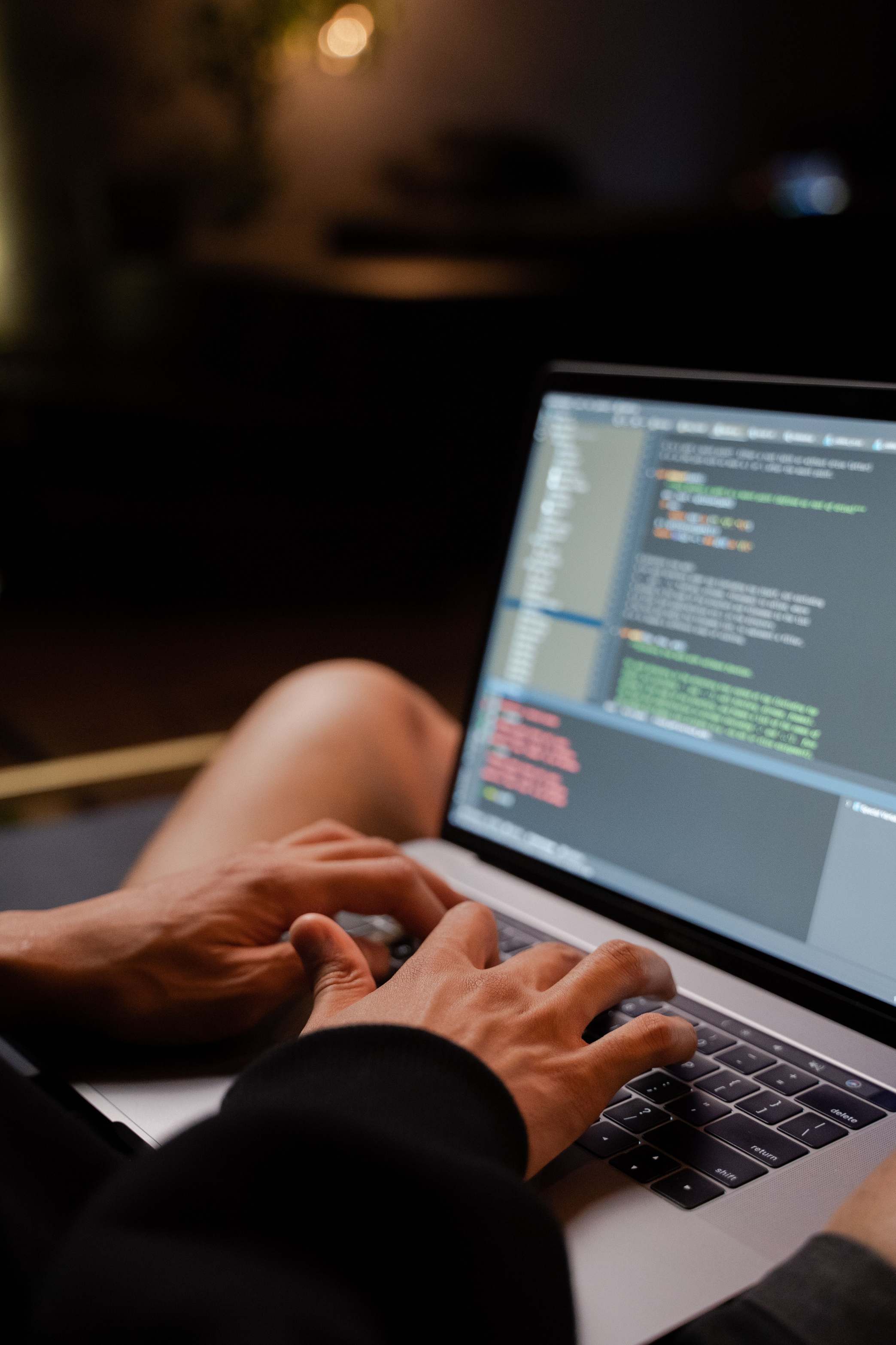 Hände an der Laptop-Tastatur mit Code auf dem Display, Entwickler am Notebook